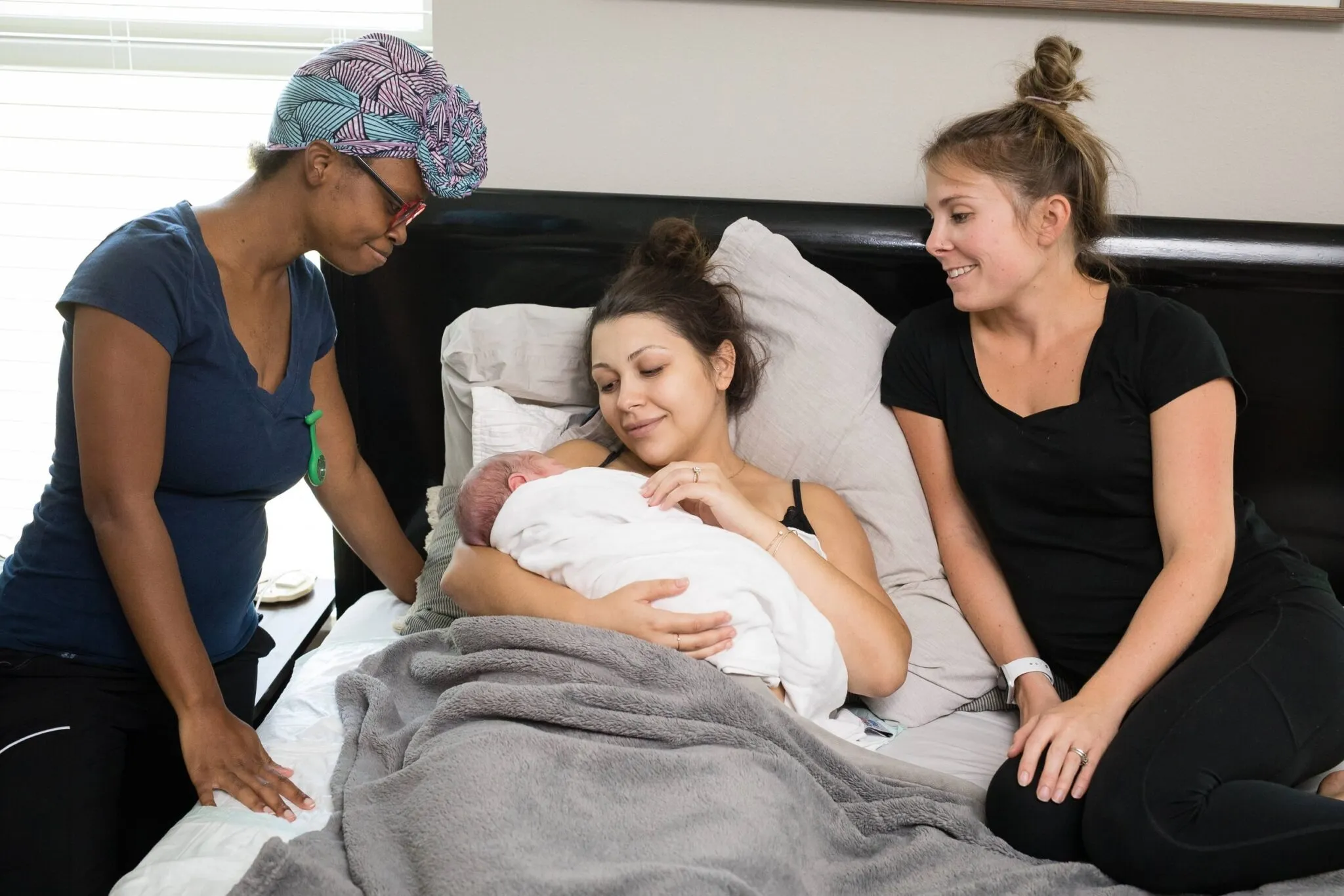 Midwives with a new mother holding her newborn after a home birth