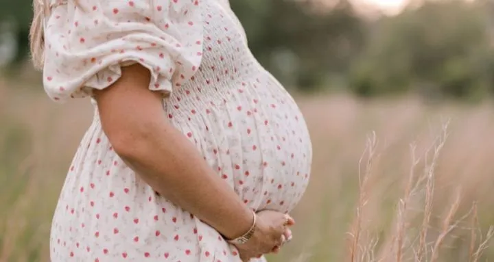 Expectant mother cradling her belly in a summer field